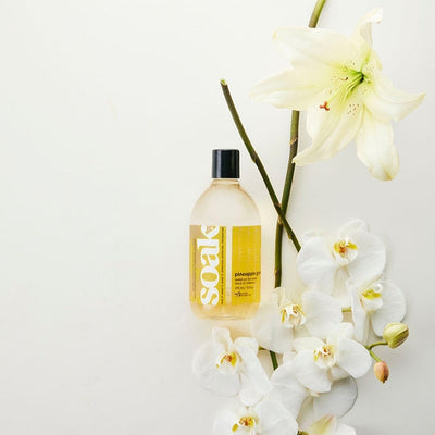 Bottle of 'Soak' with white flowers on a light background