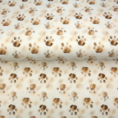 Paws - Digital Printed Cotton Jersey, SKU: 25240. A charming cotton jersey print featuring soft brown paw prints with a watercolour effect on a light cream background. OEKO-TEX certified, stretchy and breathable—ideal for pet-themed apparel, children's clothing, loungewear, and playful makes.