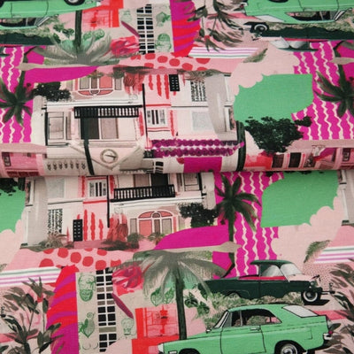 Vintage Miami Pink - Digital Printed Cotton Jersey, SKU: 25938-12. A bold, retro-inspired cotton jersey featuring digitally printed illustrations of pastel Miami buildings, classic cars, palm trees, and pops of neon pink and green. Soft and stretchy, ideal for fun and colourful t-shirts, dresses, and children's garments.