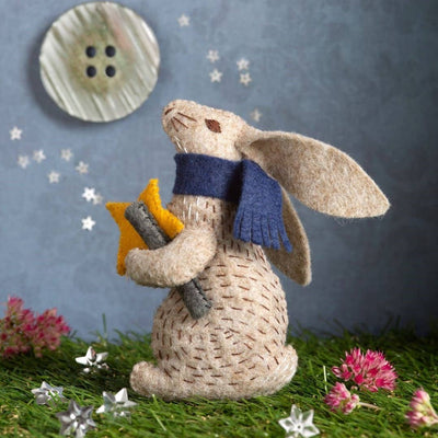 Textured bunny figurine wearing a blue scarf holding a yellow star, with a button and flowers in the background. Prof Hare Stargazer Felt Craft Mini Kit – Complete DIY sewing kit with felt, thread, needle, stuffing, and instructions to make a hare decoration