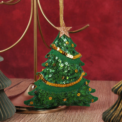 Green sequin Christmas tree ornament with gold accents on a red background.  Christmas Sequin Tree – Felt Decoration Kit (SKU GCK243) with pre-cut green and red felt shapes, sequins, thread, needle, and stuffing for making a sparkling handmade Christmas ornament,