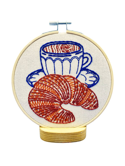 Embroidery hoop with a cup of coffee and croissant design on a white background